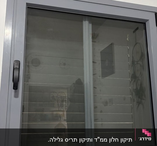 חלון עם תריסים אפורים על קיר לבן